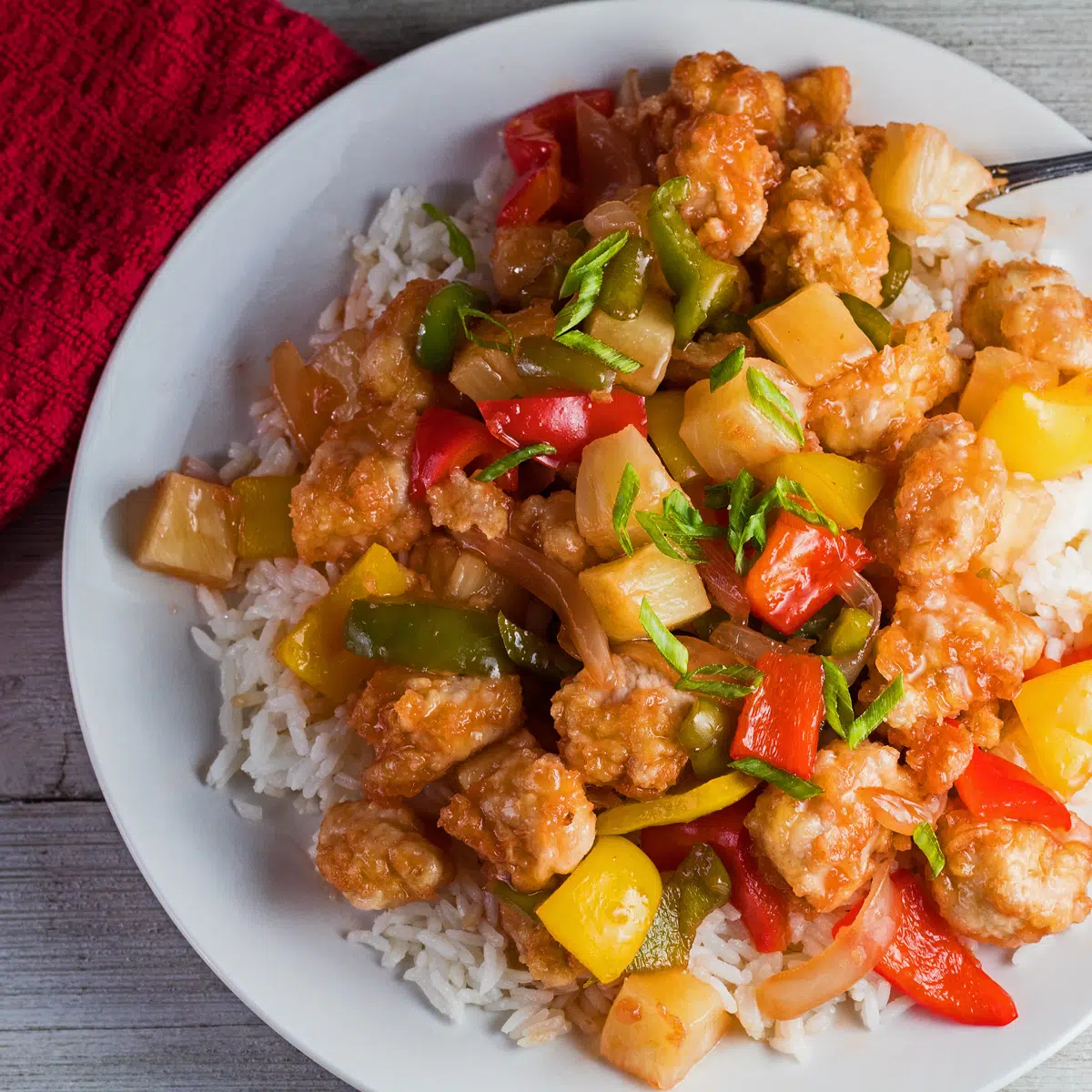 Delightfully tangy sweet and sour pork served on white plate.