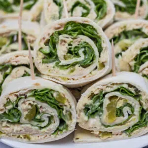 Tuna salad pinwheel sandwiches cut and stacked on plate.