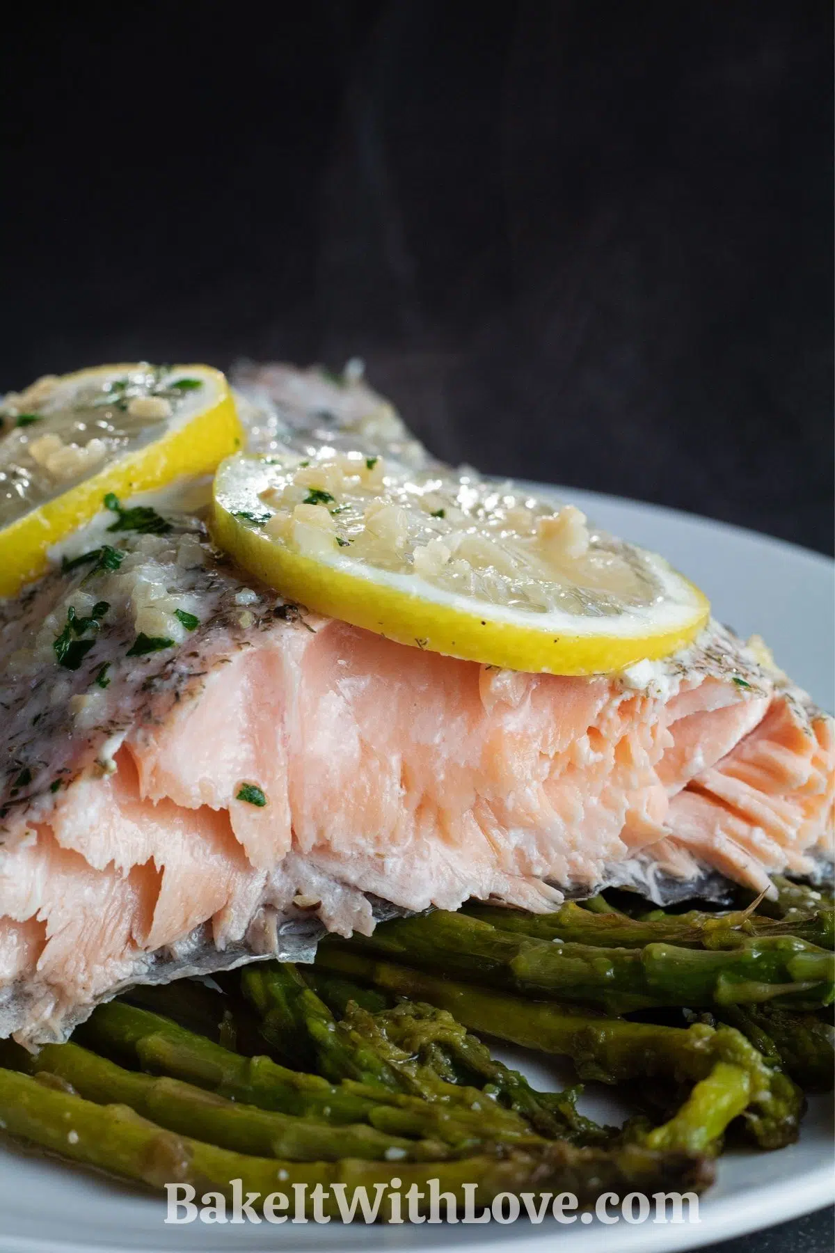 Baked salmon in foil served with asparagus on white plate.