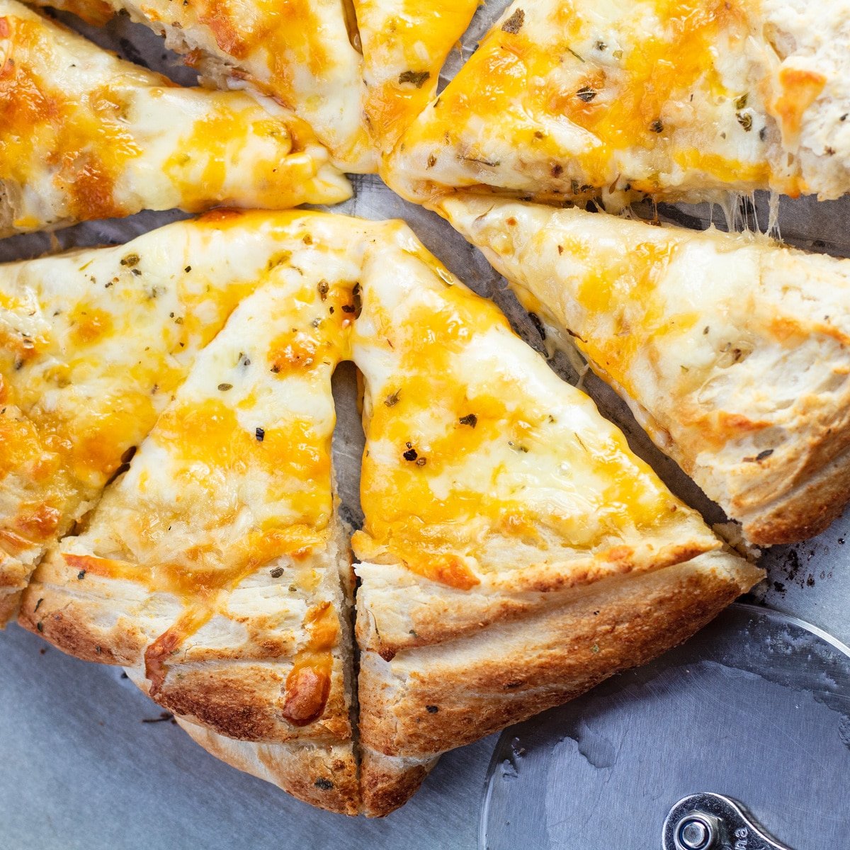 Kolay, peynirli sarımsaklı pizza dilimlenir ve servis edilir.