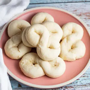 Baked kringla cookies served on dustry pink plate.