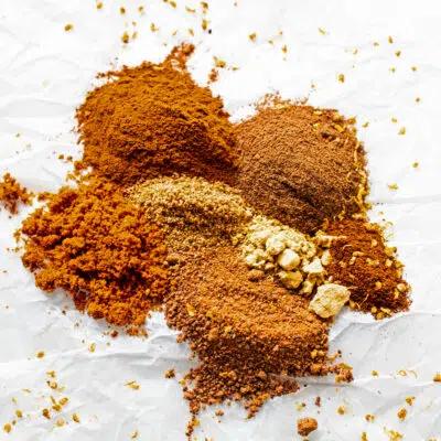 Mixed spice ingredients piled on white parchment paper.
