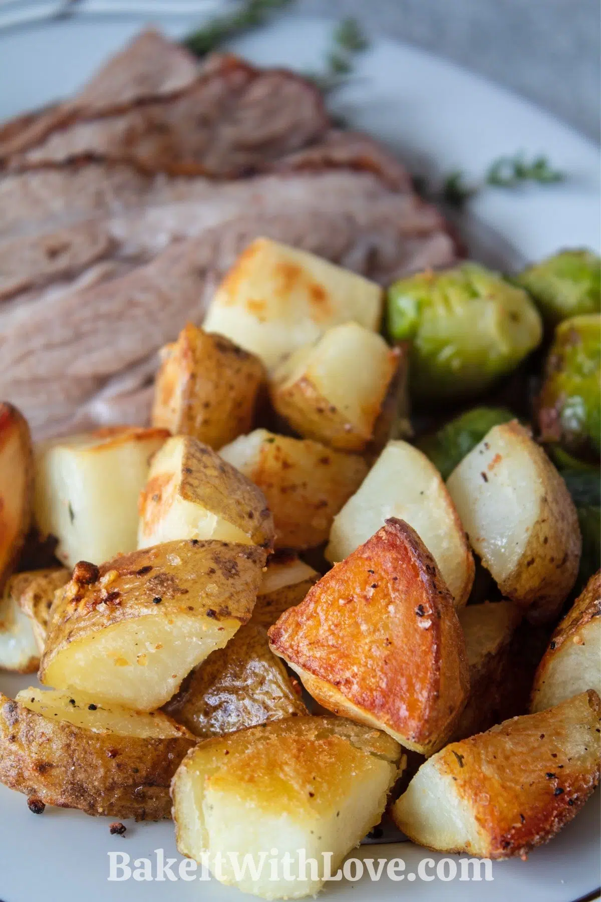 Crispy oven roasted potatoes served on platter with roast and vegetables.