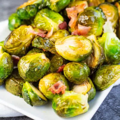 Hearty smoked brussel sprouts tossed in batter with bacon and served on white platter.