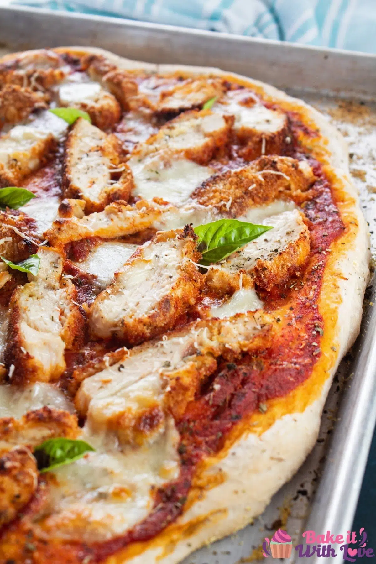 Chicken parmesan pizza on baking sheet with light blue background.o