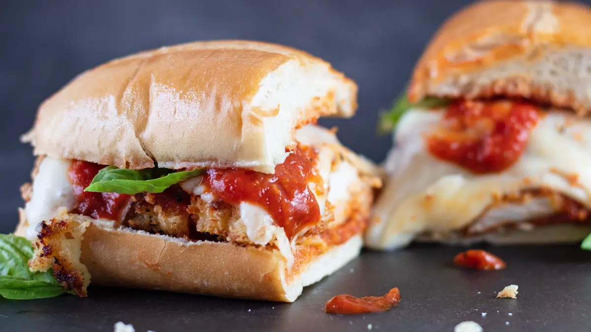 Wide angle of the cut chicken parmesan sandwich.