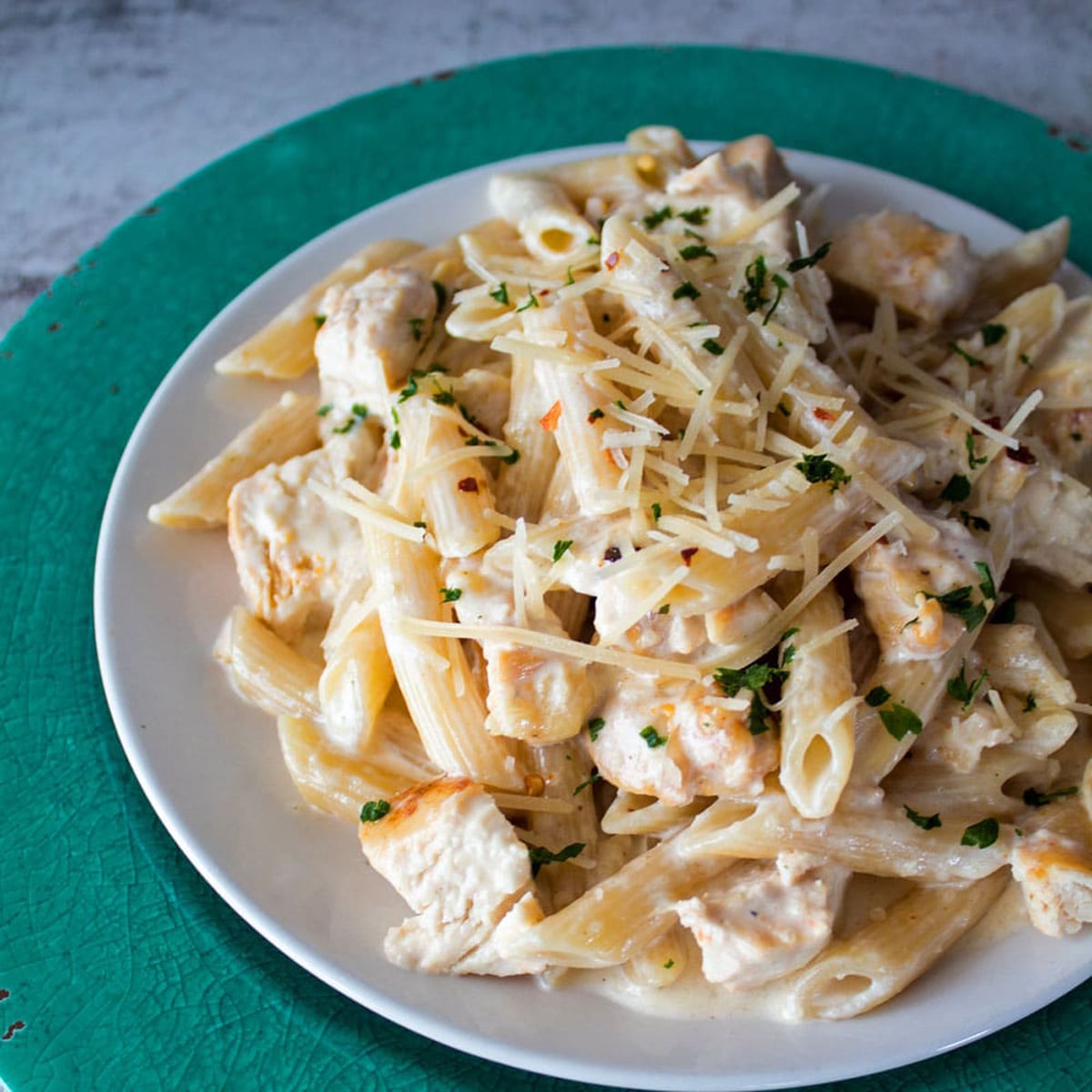 Kip Alfredo op een wit bord gegarneerd met Parmezaanse kaas.