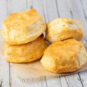 Air fryer biscuits cooked until golden and stacked on parchment paper.