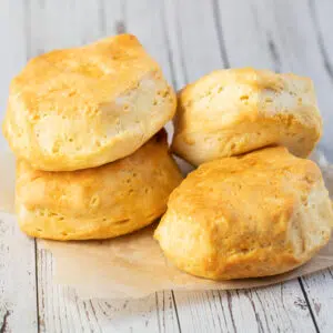 Air fryer biscuits cooked until golden and stacked on parchment paper.
