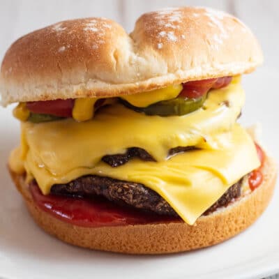 Air fryer frozen burger on bun with cheese and condiments.