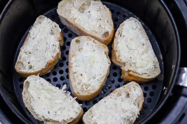 Process photo 4 of slices of bread with garlic spread in the air fryer basket.