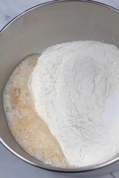 Process photo 3 of adding the remaining dough ingredients in with the yeast mixture.