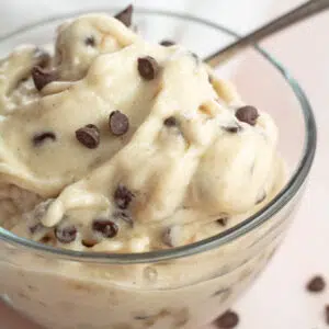 Mint chocolate chip nice cream in clear bowl topped with mini chocolate chip morsels.