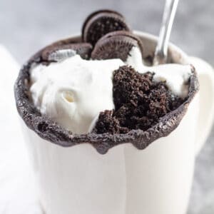 Oreo mug cake servito con panna montata e mini Oreo extra.