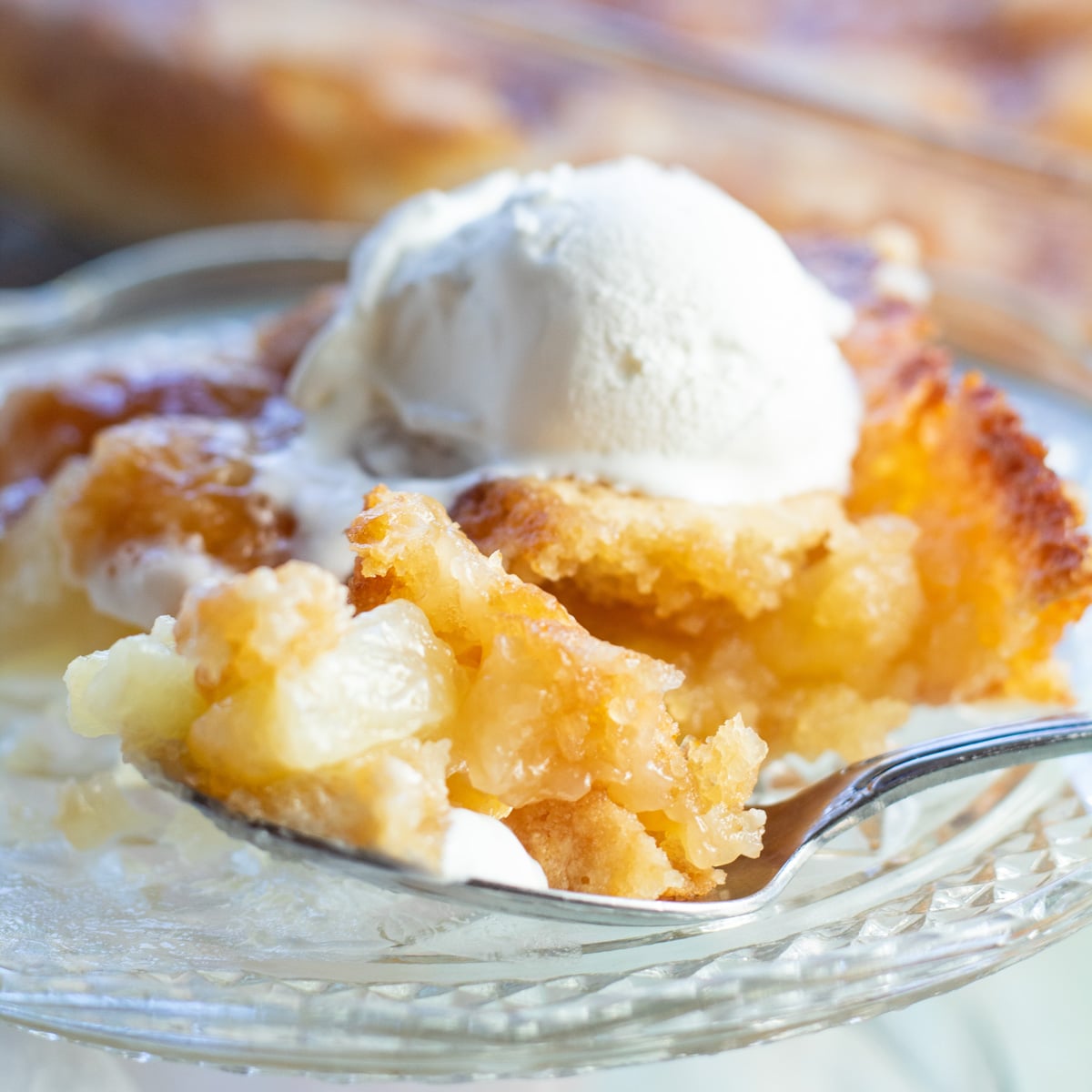 Pastel de volcado de piña servido en un plato de postre de vidrio.