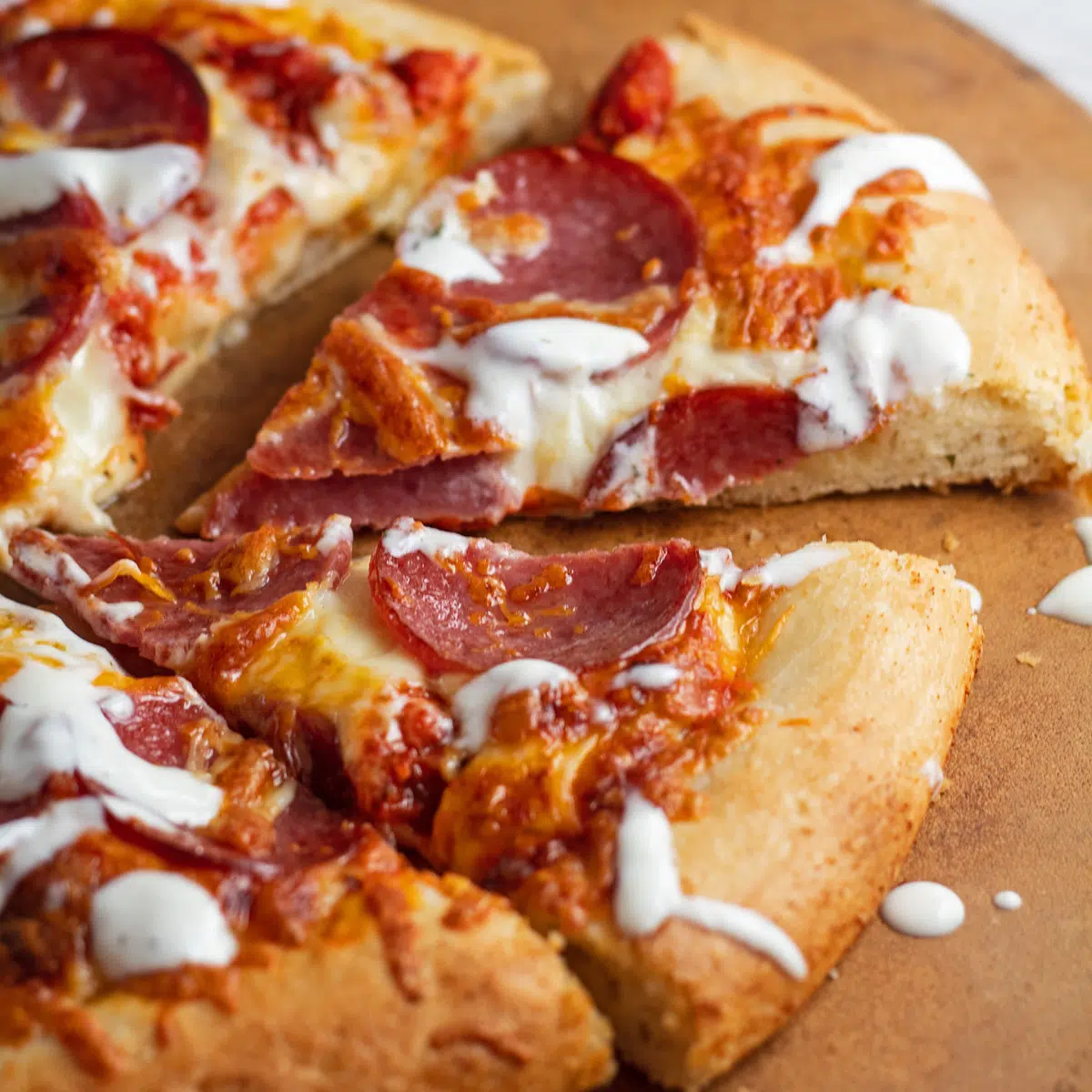 Sliced pizza drizzled with pizza aioli.