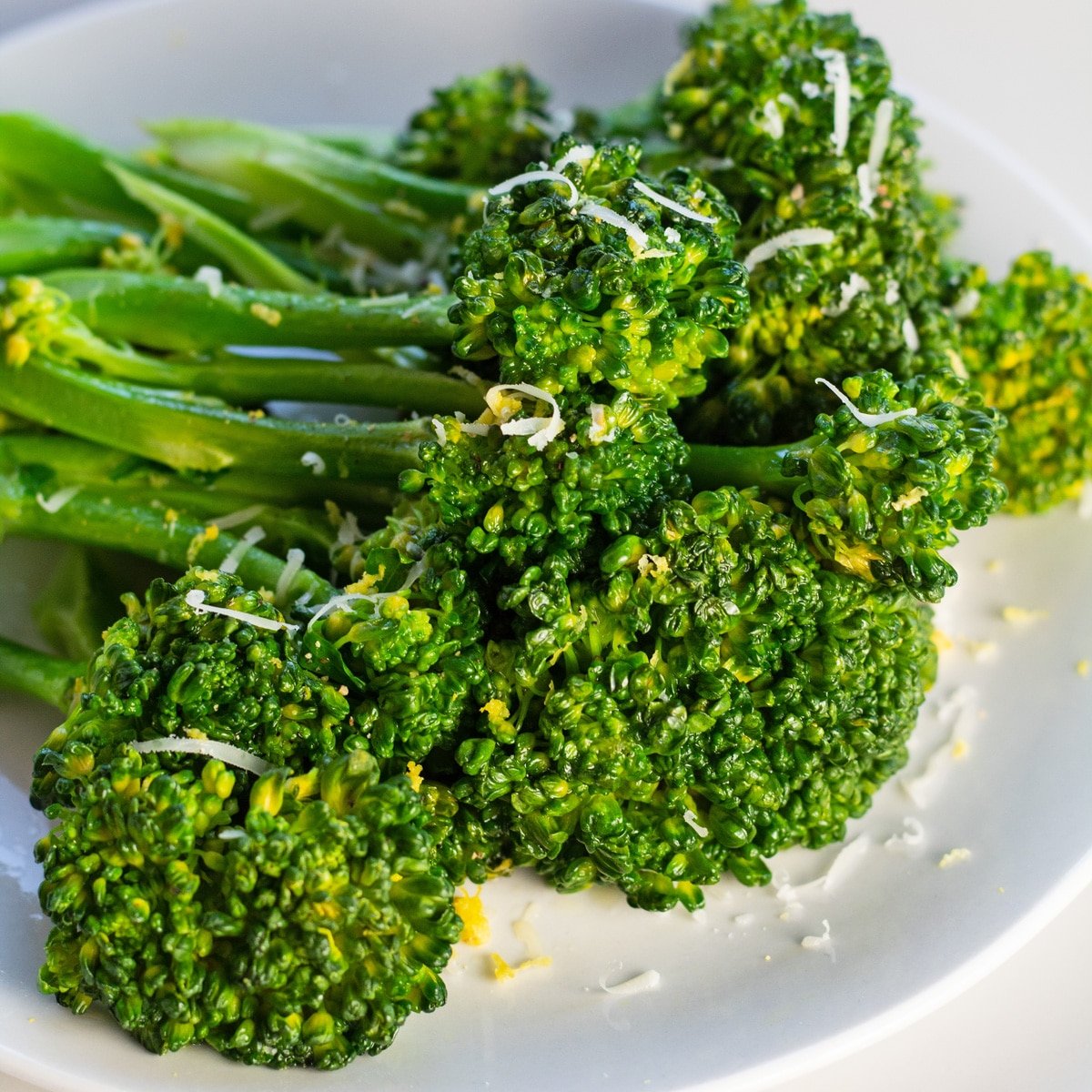 Broccolini salteado decorado guarnecido e servido em prato branco.