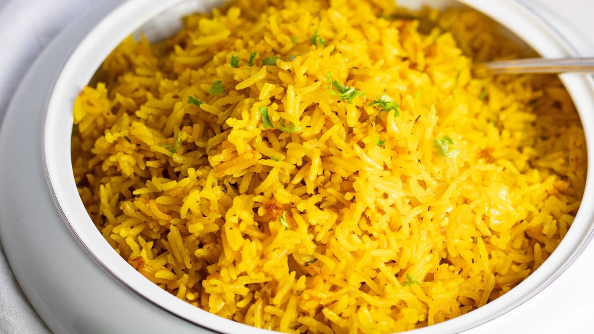 Wide overhead image of the turmeric rice in serving dish.