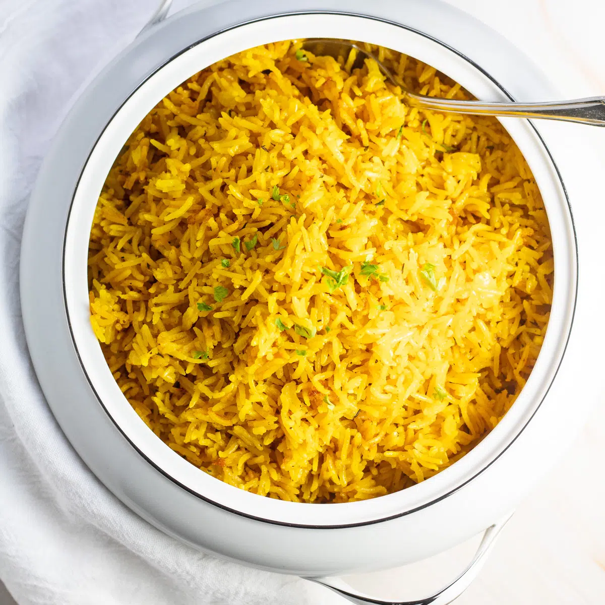 Turmeric rice in serving dish on light background.