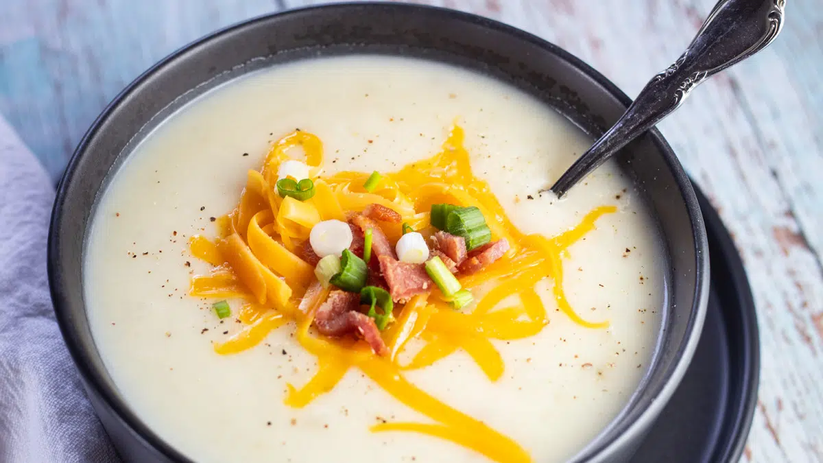 Wide image of the dishes 4 ingredient potato soup served in black bowl.