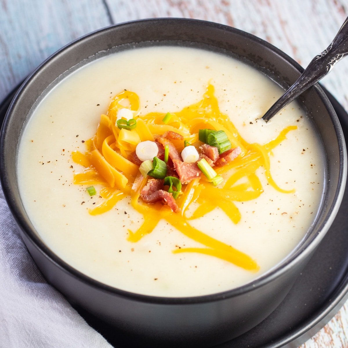 Sup kentang 4 bahan disajikan dengan keju cheddar parut, bacon renyah, dan irisan daun bawang.