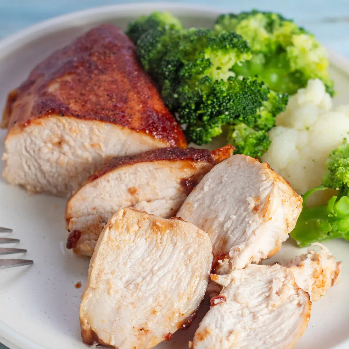 Dilimlenmiş pişmiş barbekü tavuk göğsü, buharda pişmiş brokoli ile servis edilir.