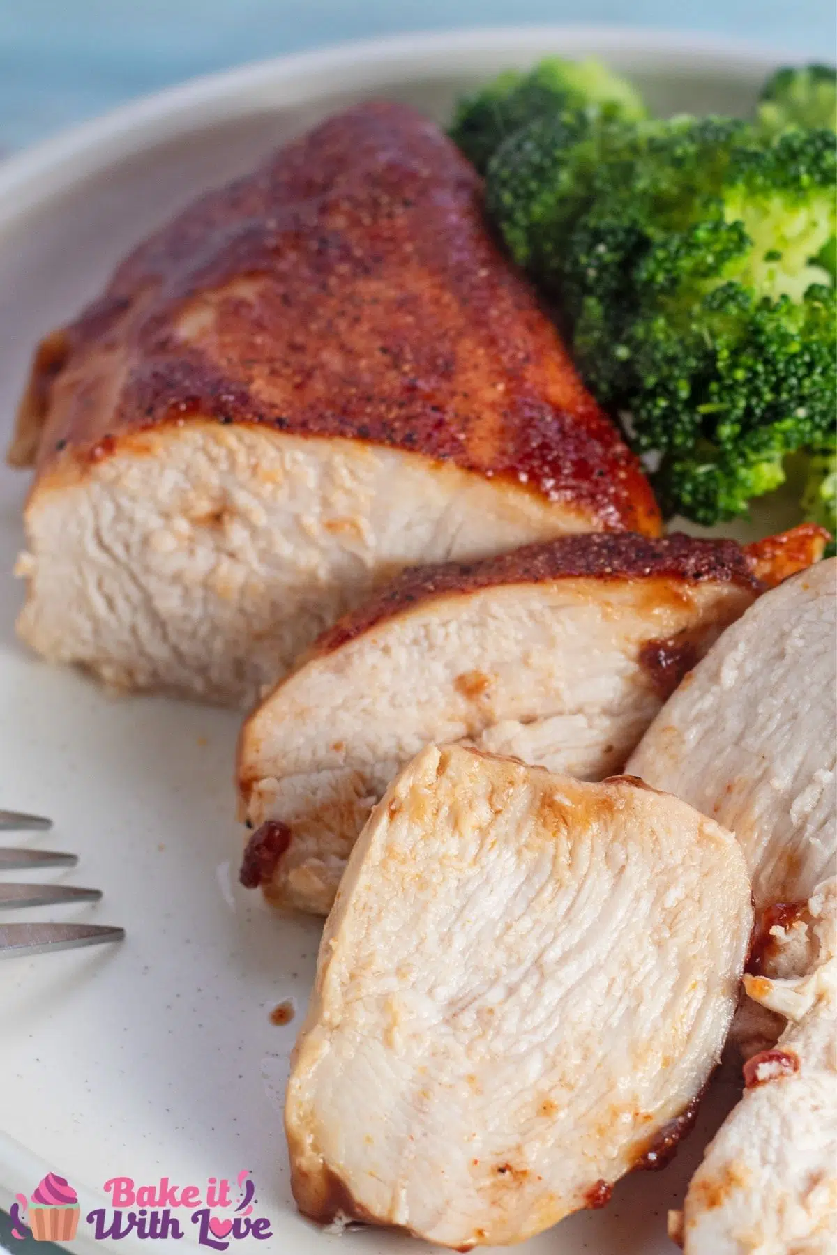 Tall image of the sliced baked bbq chicken breast on white plate.