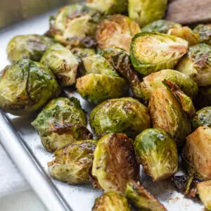 Balsamic roasted brussel sprouts on sheet pan with wooden spatula.