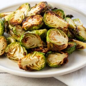 Air fryer brussel sprouts crisped and served on white plate.