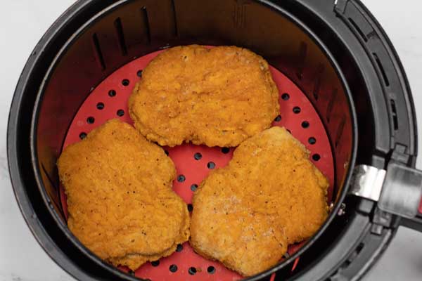 process photo 1 of the frozen country fried steaks in air fryer basket.