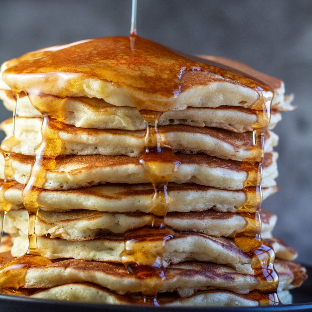 Stack of Bisquick pancakes with syrup drizzling down them.