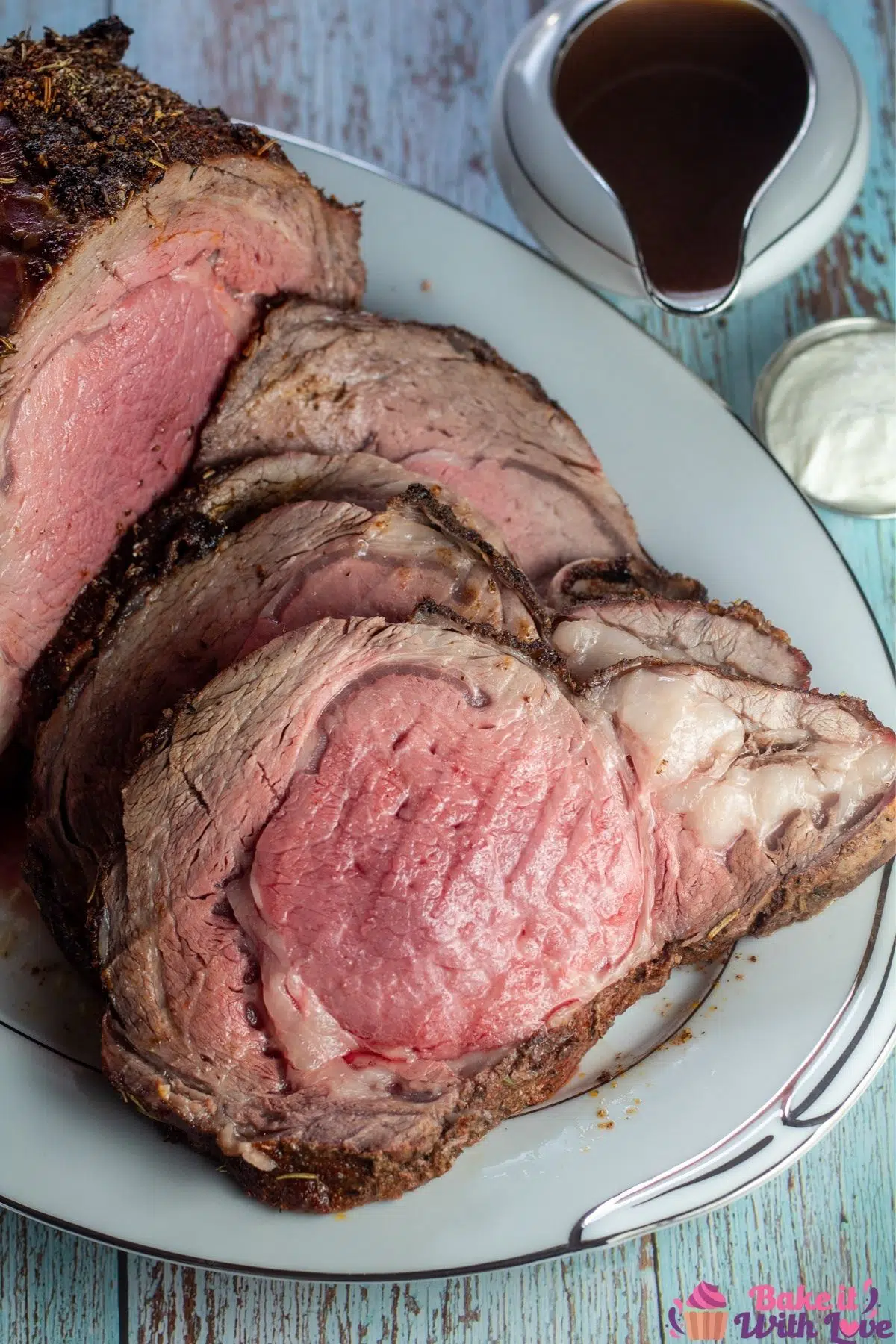Tall overhead image of the sliced boneless prime rib roast with au jus and horseradish on the side.