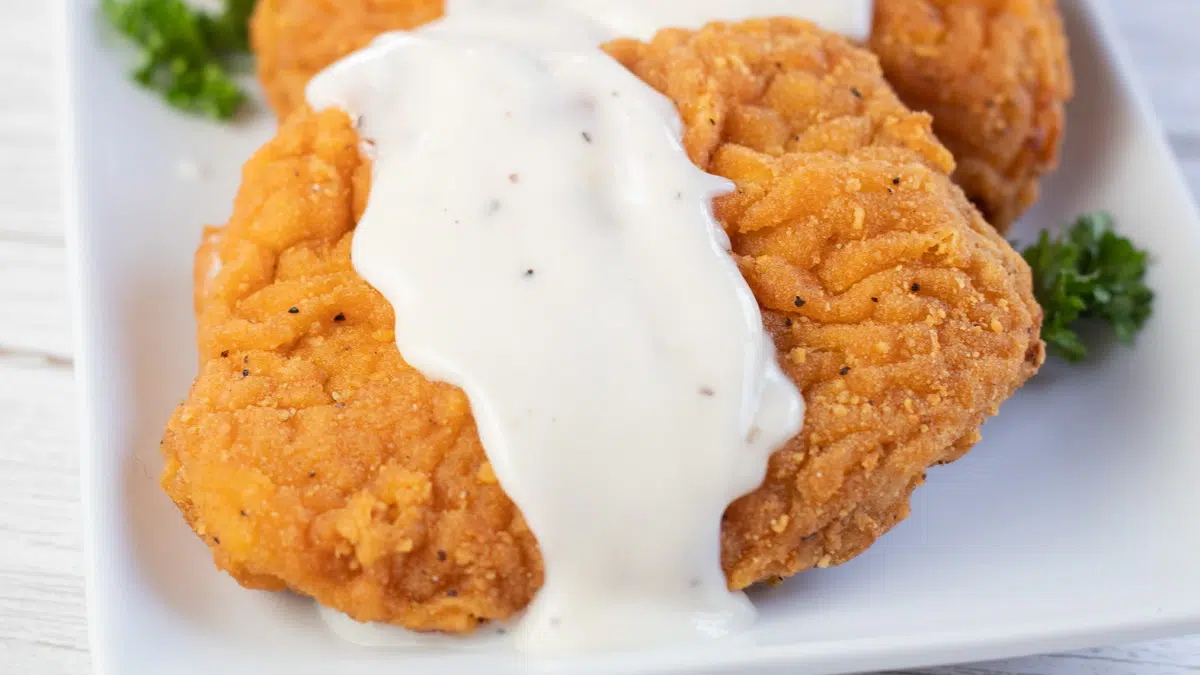 Wide image of the country gravy over country fried steak.