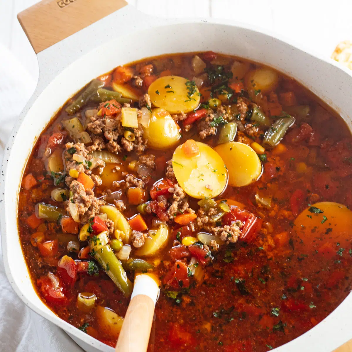 Hamburger soup in stock pot with white ladle rested on side.