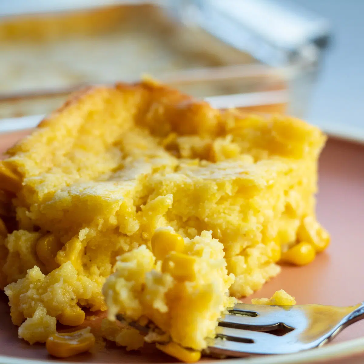 Jiffy corn casserole on light plate with a bite on fork.