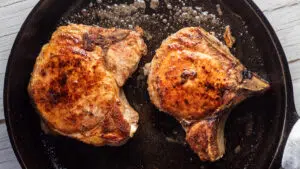 Image of seared pork chops in a pan.
