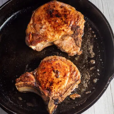 Image of two seared pork chops in a pan.
