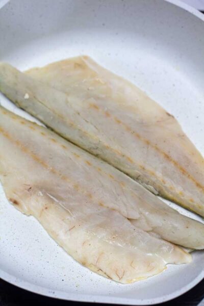Process photo 1 of seasoned sea bass in skillet.