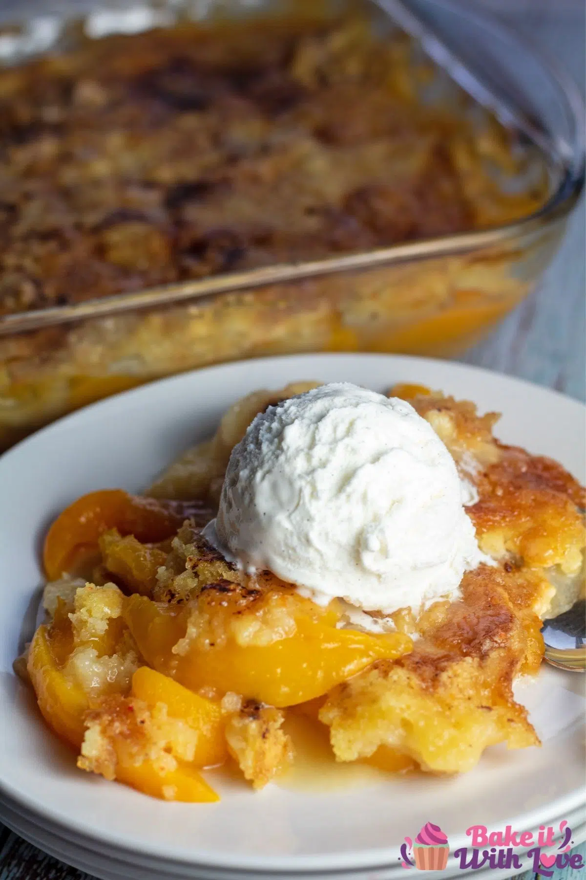 Peach dump cake on white plate with whipped cream.