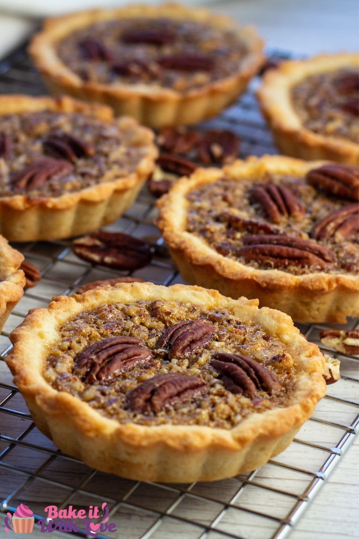 Tall closeup of the pecan tartlets on cooling rack.