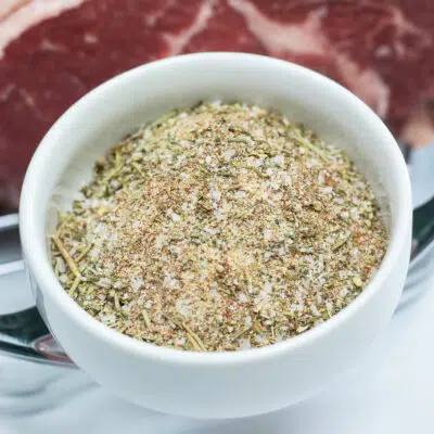 Prime rib rub combined in white bowl with prime rib in background.