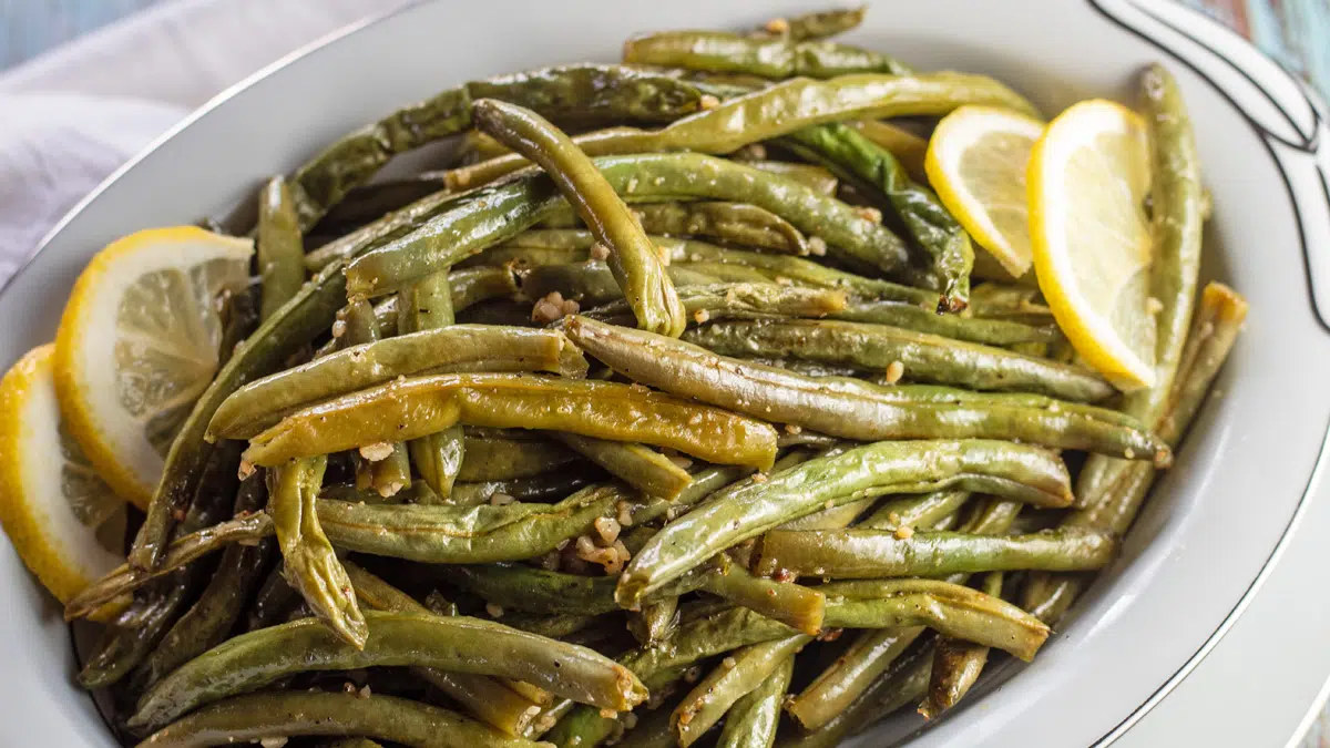 Wide image of the roasted green beans with lemon slices for garnish.