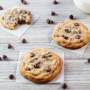 Small batch chocolate chip cookies on wooden grain background with scattered chips.