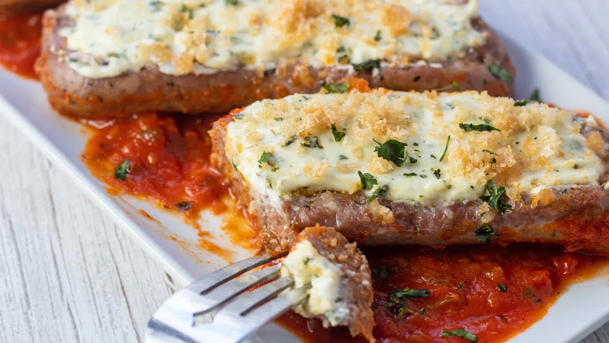 Wide image of stuffed Italian sausages in sauce.
