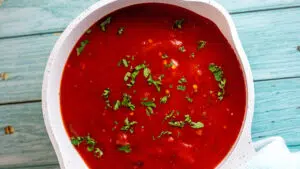 Arrabbiata sauce in saucepan on light blue background.