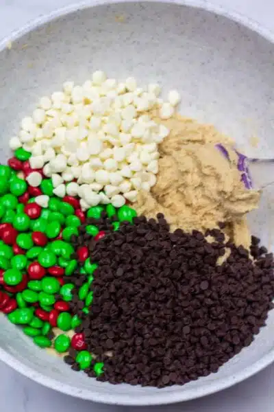 Process photo 6 add Christmas M&Ms, mini chocolate chips, and white chocolate chips.