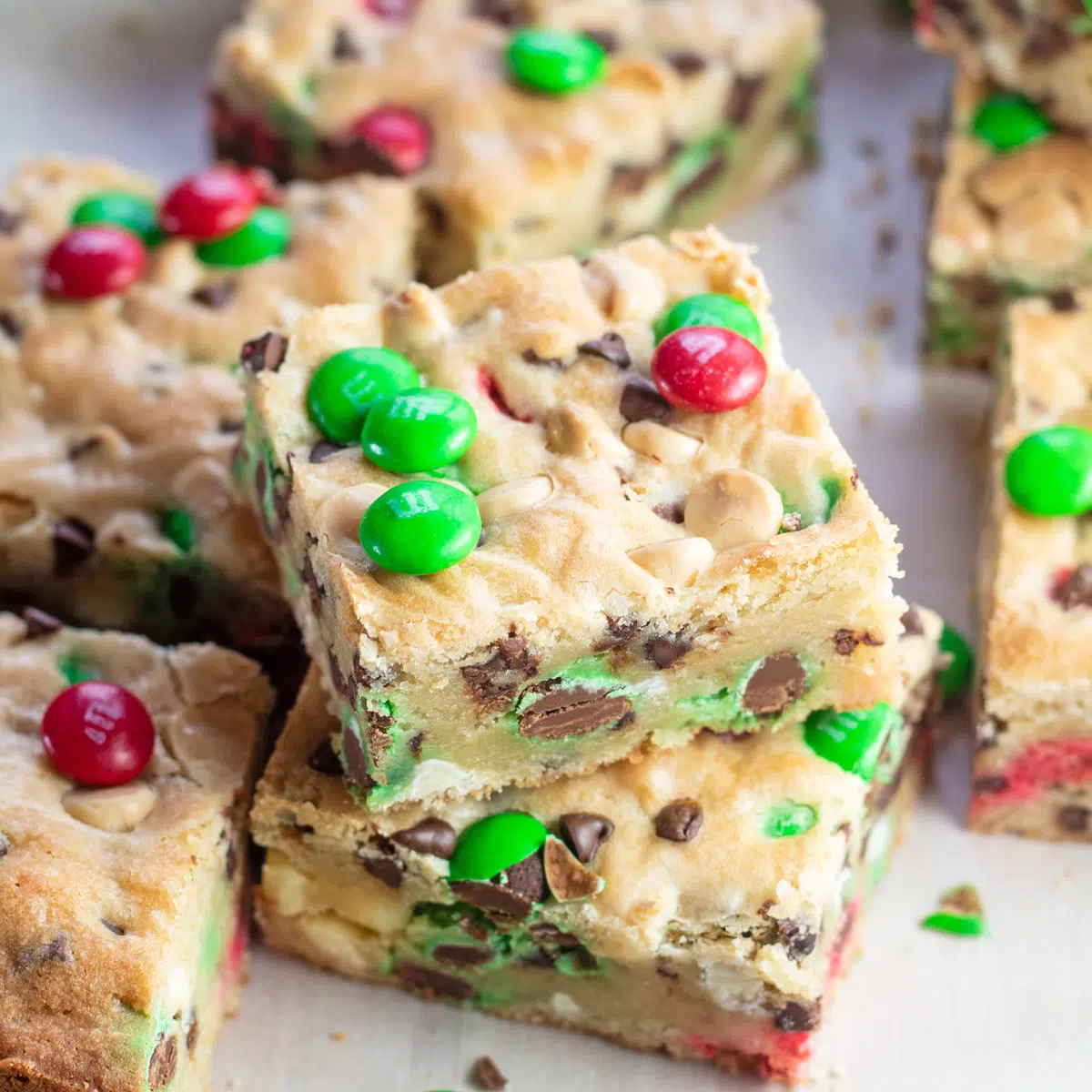 Christmas MM cookie bars stacked with more Christmas M&Ms around them.