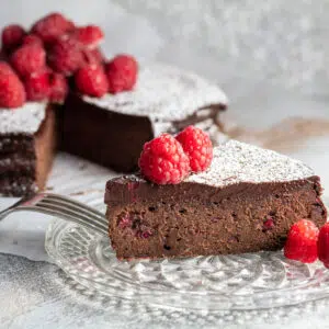 Flourless chocolate raspberry cake sliced with raspberries on top.