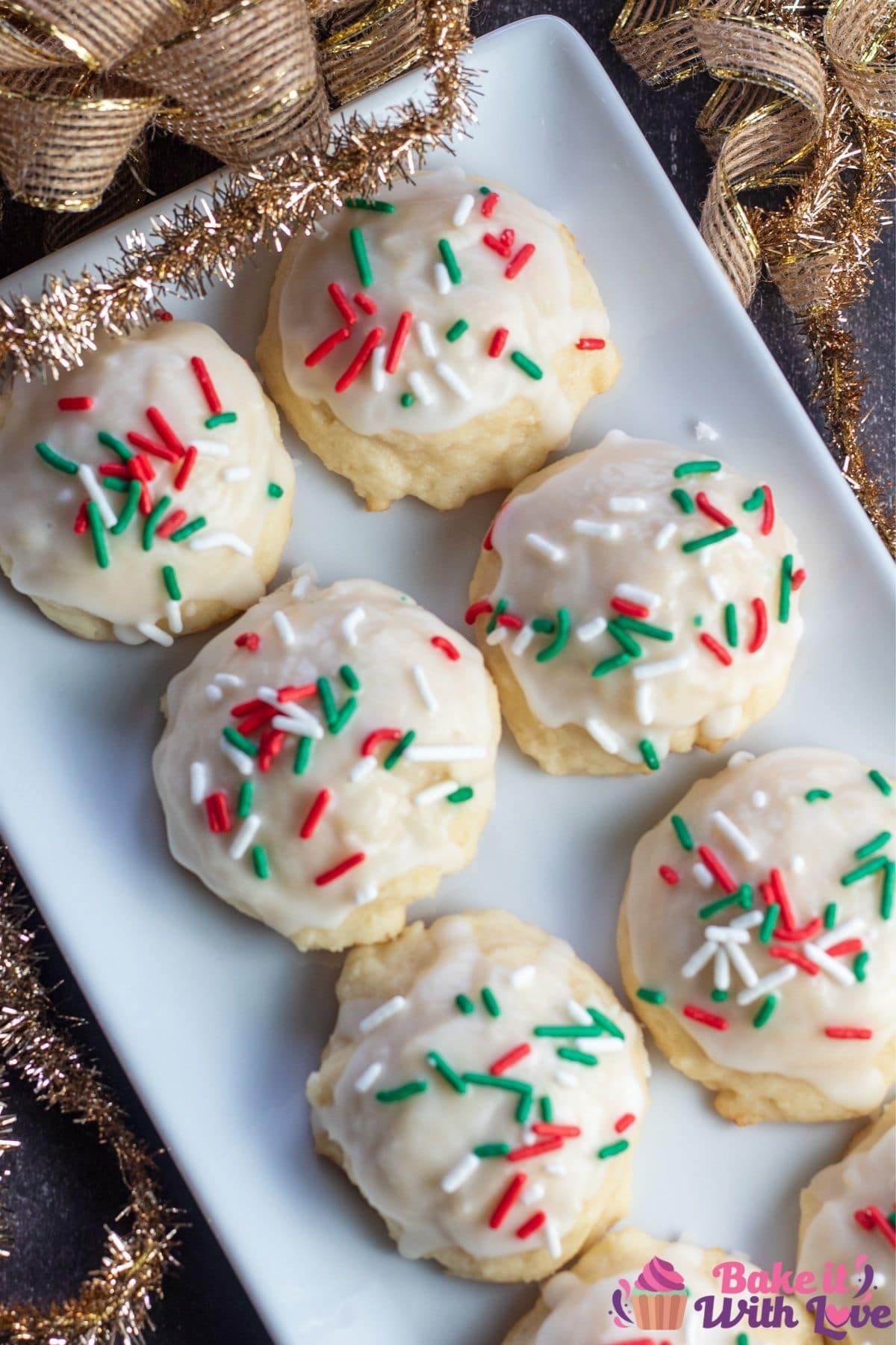 Tall overhead image of the Italian ricotta cookies served on white tray with gold holiday ribbons in background.