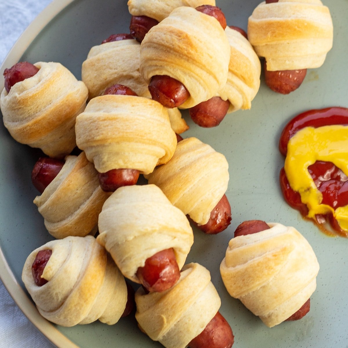 Lil smokies pigs in a blanket served with ketchup and yellow mustard.